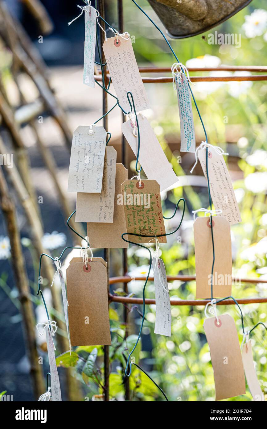 Etichette/etichette di carta o di carta appese su una struttura di memoria in giardino Foto Stock