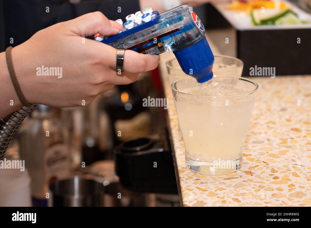 La mano del barista femminile aggiunge bevande gassate alla fontana alle bevande alcoliche. Foto Stock