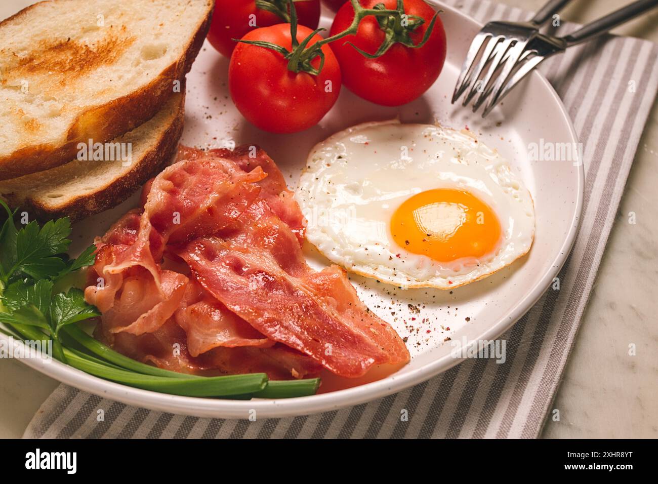 Fruehstueck, Spiegelei, Speck und Brot, mit Kirsche, auf einem hellen Hintergrund, hausgemacht, keine Menschen Foto Stock