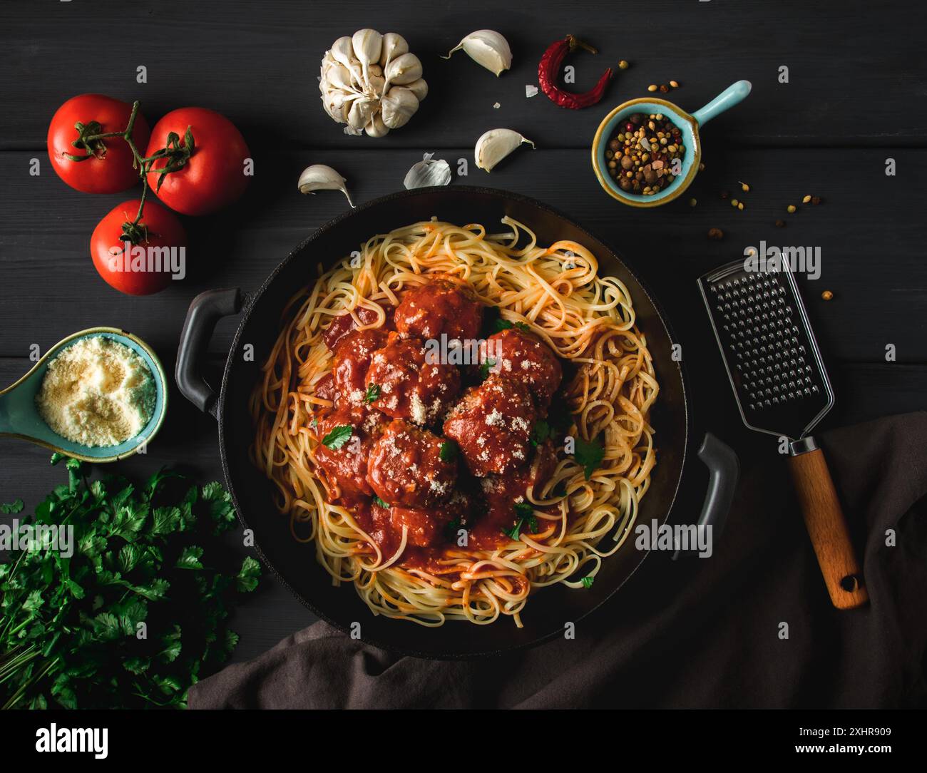 Spaghetti und Fleischbaellchen in Tomatensauce, auf einem dunklen Holztisch, Gewuerze, Draufsicht, keine Personen Foto Stock