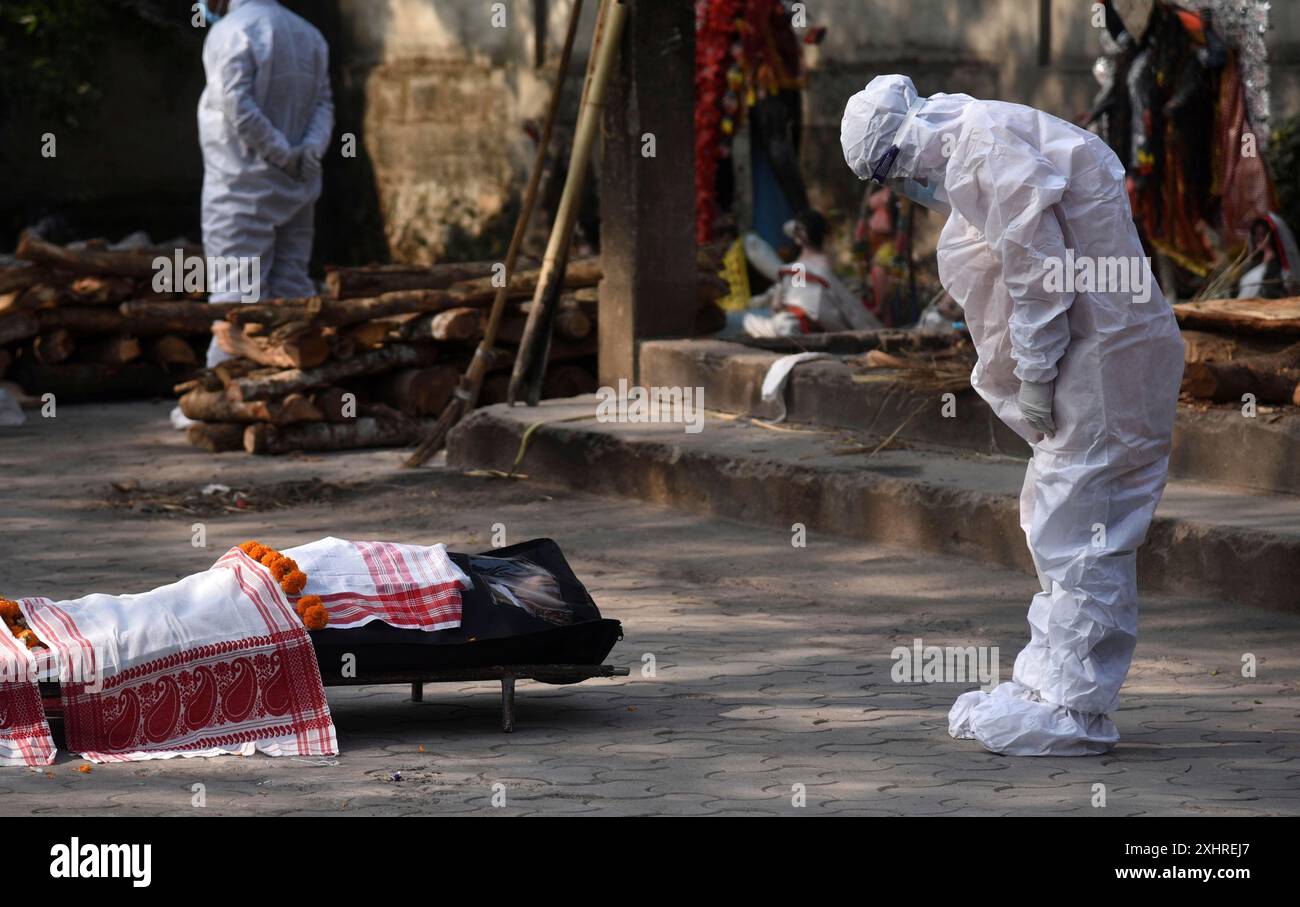 Membri della famiglia che indossano kit DPI che eseguono gli ultimi riti di una persona morta per la malattia da coronavirus COVID-19, in un terreno di cremazione a Guwahati, Assam Foto Stock