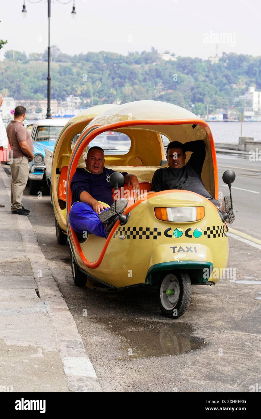 L'Avana, Cuba, grandi Antille, Caraibi, America centrale, America, taxi giallo a tre ruote con due uomini all'interno, parcheggiato su una strada con vista Foto Stock