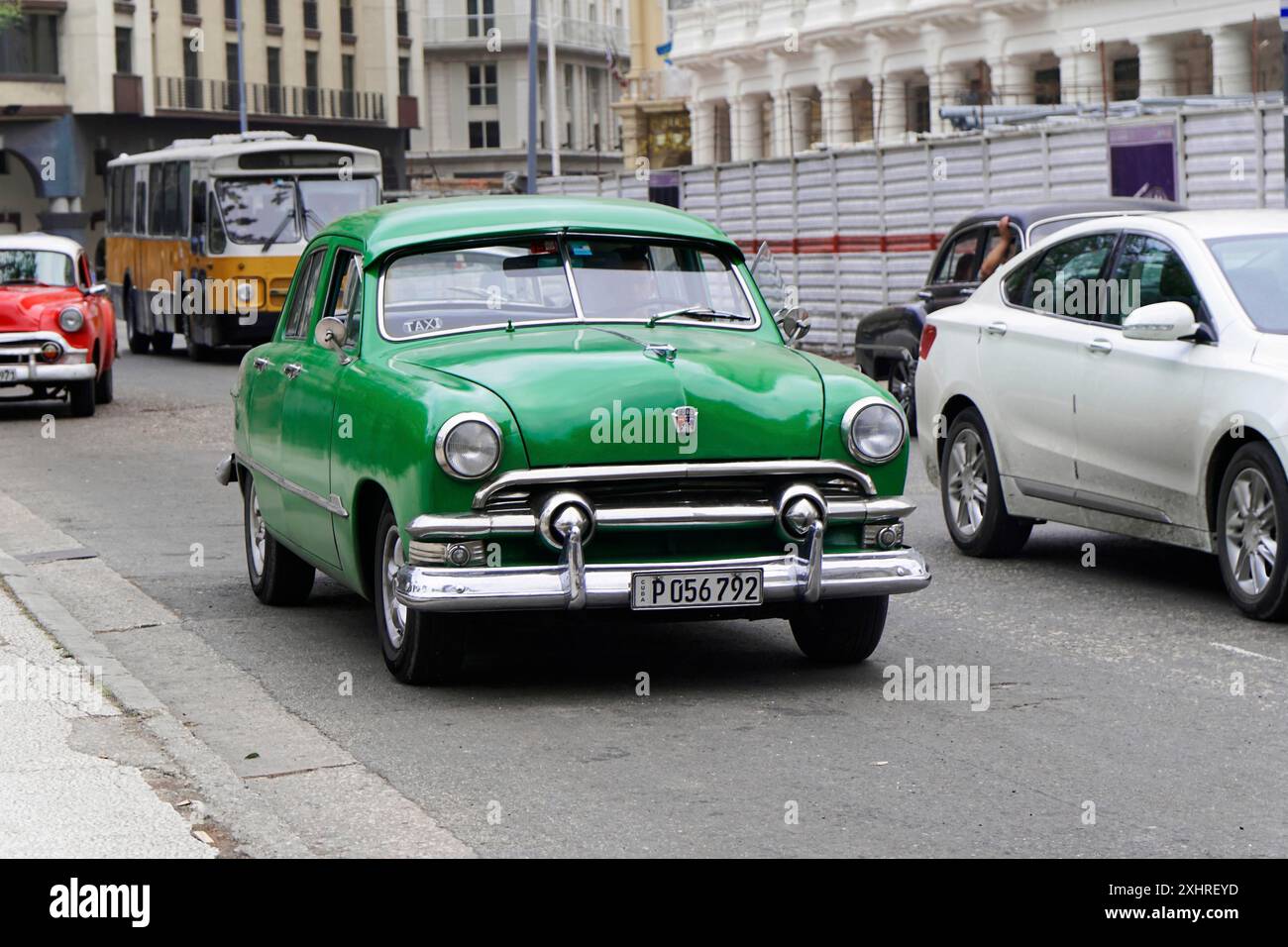 L'Avana, Cuba, l'America centrale, un'auto d'epoca verde attraversa una strada cittadina insieme alle auto moderne Foto Stock