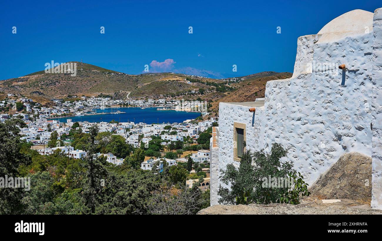 Vista di una città costiera e di un edificio bianco su una collina con cielo blu e mare sullo sfondo, Monastero tis Apokalipsis, Patmos, Dodecaneso, greco Foto Stock