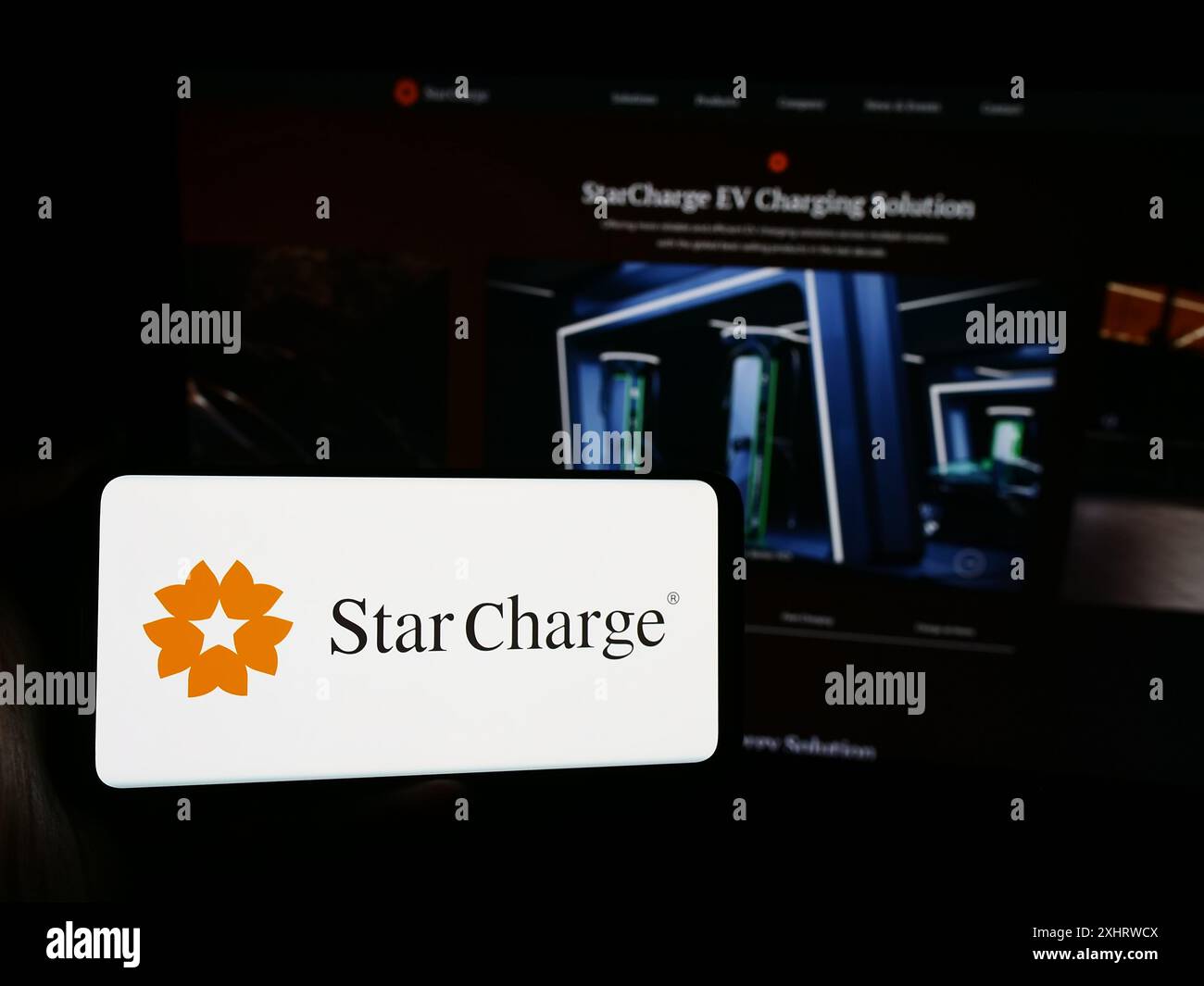 Persona con smartphone con logo della società di ricarica di veicoli elettrici di Singapore Star Charge davanti al sito Web. Mettere a fuoco il display del telefono. Foto Stock