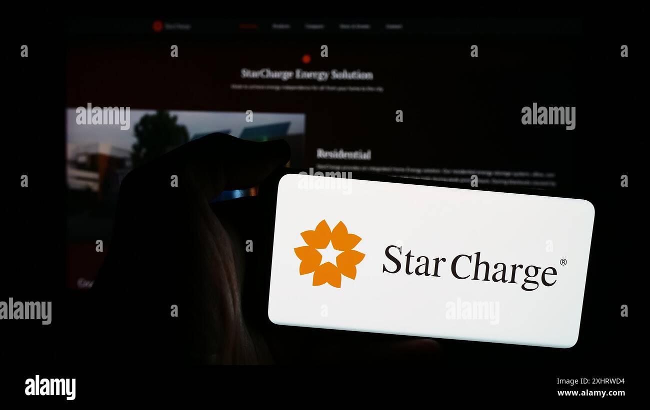 Persona che possiede un telefono cellulare con il logo della società di ricarica per veicoli elettrici di Singapore Star Charge davanti alla pagina Web. Mettere a fuoco il display del telefono. Foto Stock