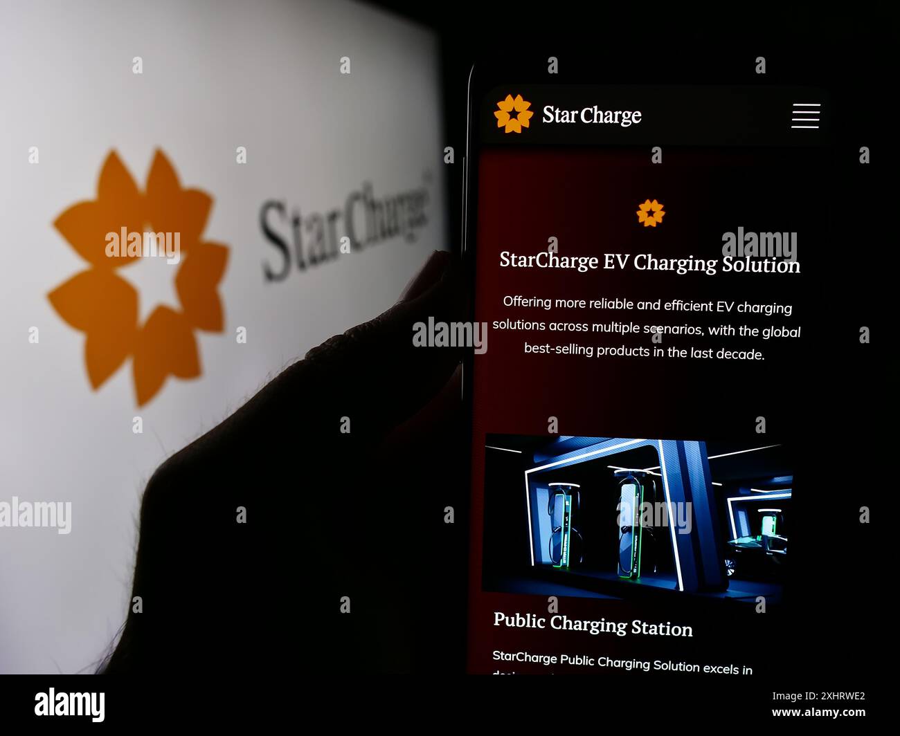 Persona con smartphone con pagina Web della società di ricarica di veicoli elettrici di Singapore Star Charge con logo. Messa a fuoco al centro del display del telefono. Foto Stock