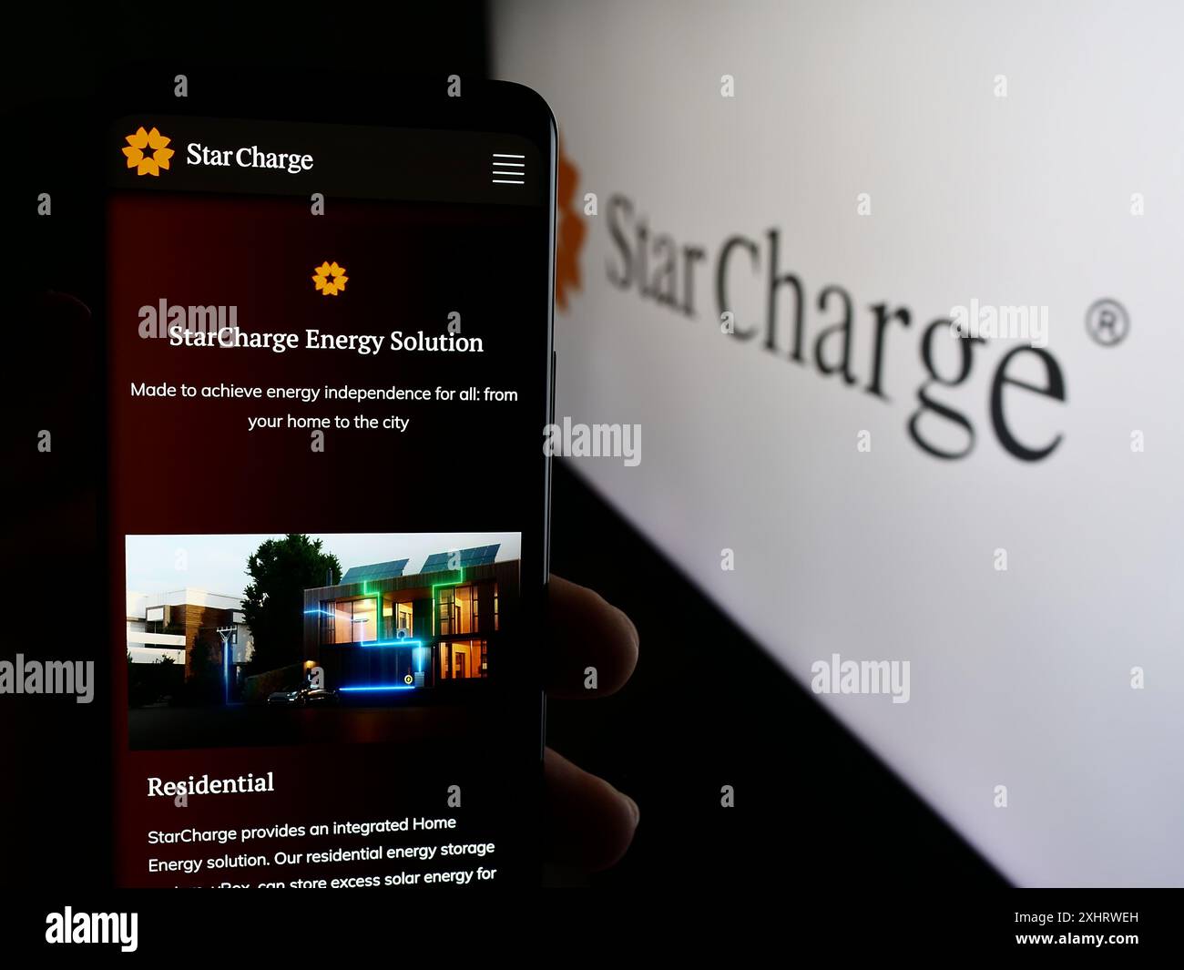 Persona che possiede un cellulare con pagina Web della società di ricarica per veicoli elettrici di Singapore Star Charge con logo. Messa a fuoco al centro del display del telefono. Foto Stock