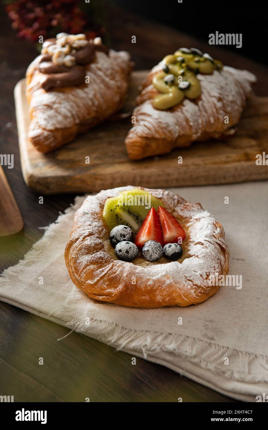 Pasticceria danese appena sfornata con marmellata e frutta. Sfondo di legno scuro. Foto Stock