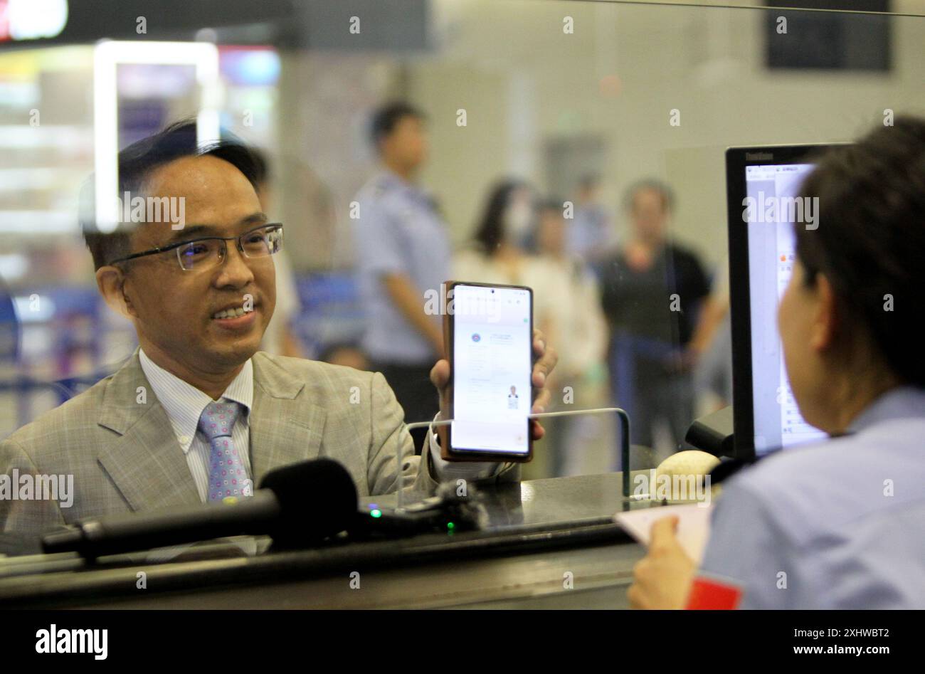 Changsha/Shanghai. 16 luglio 2024. Un uomo di nome Chung di Singapore presenta un visto elettronico rilasciato dal Government Affairs of Exit-Entry Administration Bureau dello Shanghai Public Security Bureau mentre passa attraverso le formalità di frontiera presso l'aeroporto internazionale Pudong di Shanghai, Cina orientale, il 12 luglio 2024. Crediti: Chen Haoming/Xinhua/Alamy Live News Foto Stock