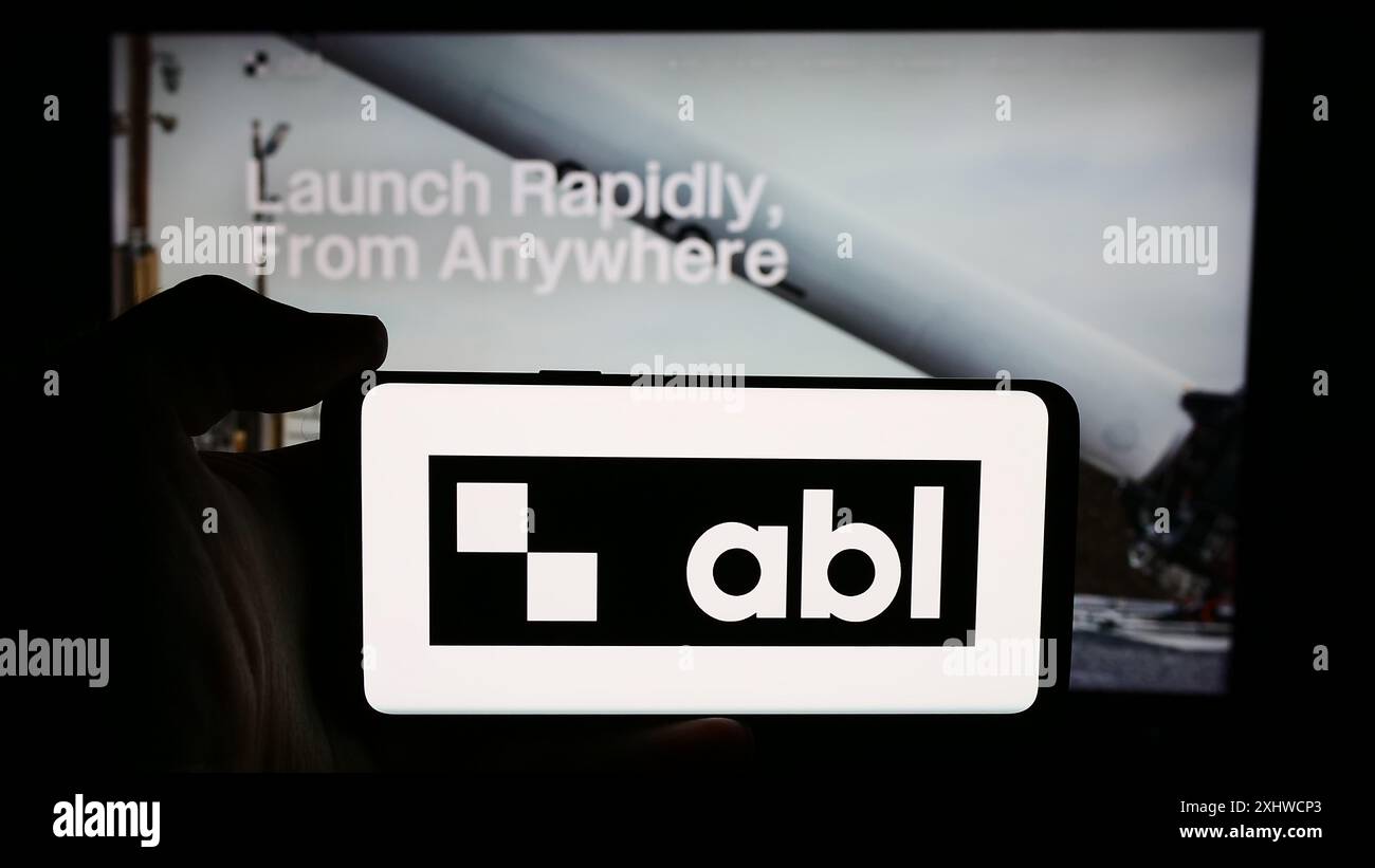 Persona che detiene un cellulare con il logo della società aerospaziale statunitense ABL Space Systems di fronte alla pagina web aziendale. Mettere a fuoco il display del telefono. Foto Stock