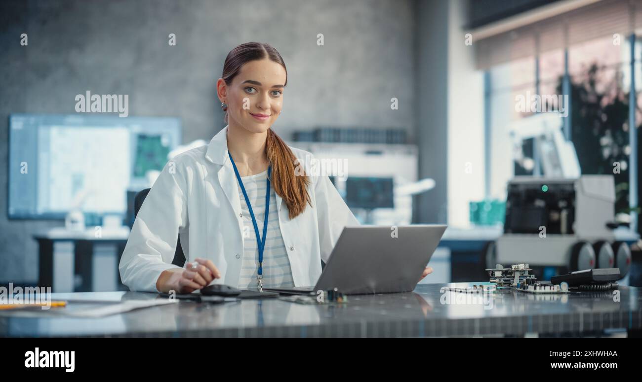 Ritratto di una giovane scienziata caucasica che usa un computer portatile, guarda la fotocamera e sorride in un laboratorio. Donna professionale sicura di sé che lavora come Lead Engineer, Monitoring Technology Projects Foto Stock