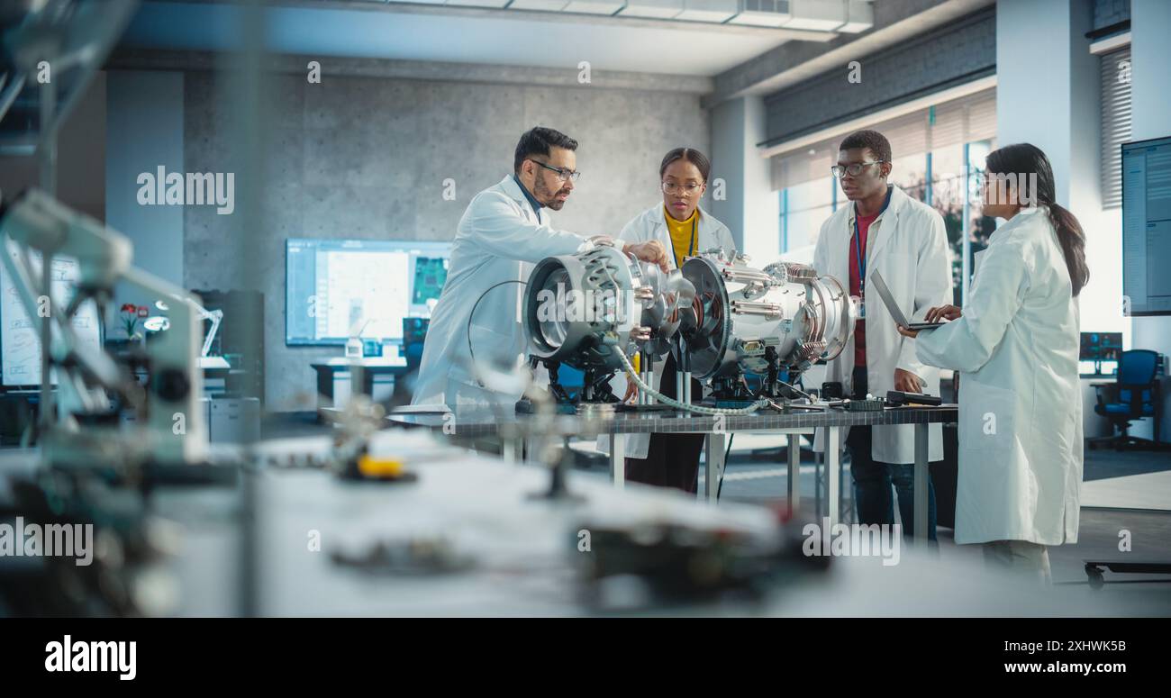 Giovane ingegnere nero donna che guida il suo team, analizzando e ricercando come funziona un futuristico motore Turbofan. Scienziati diversi che sviluppano tecnologie innovative in impianti industriali ad alta tecnologia Foto Stock