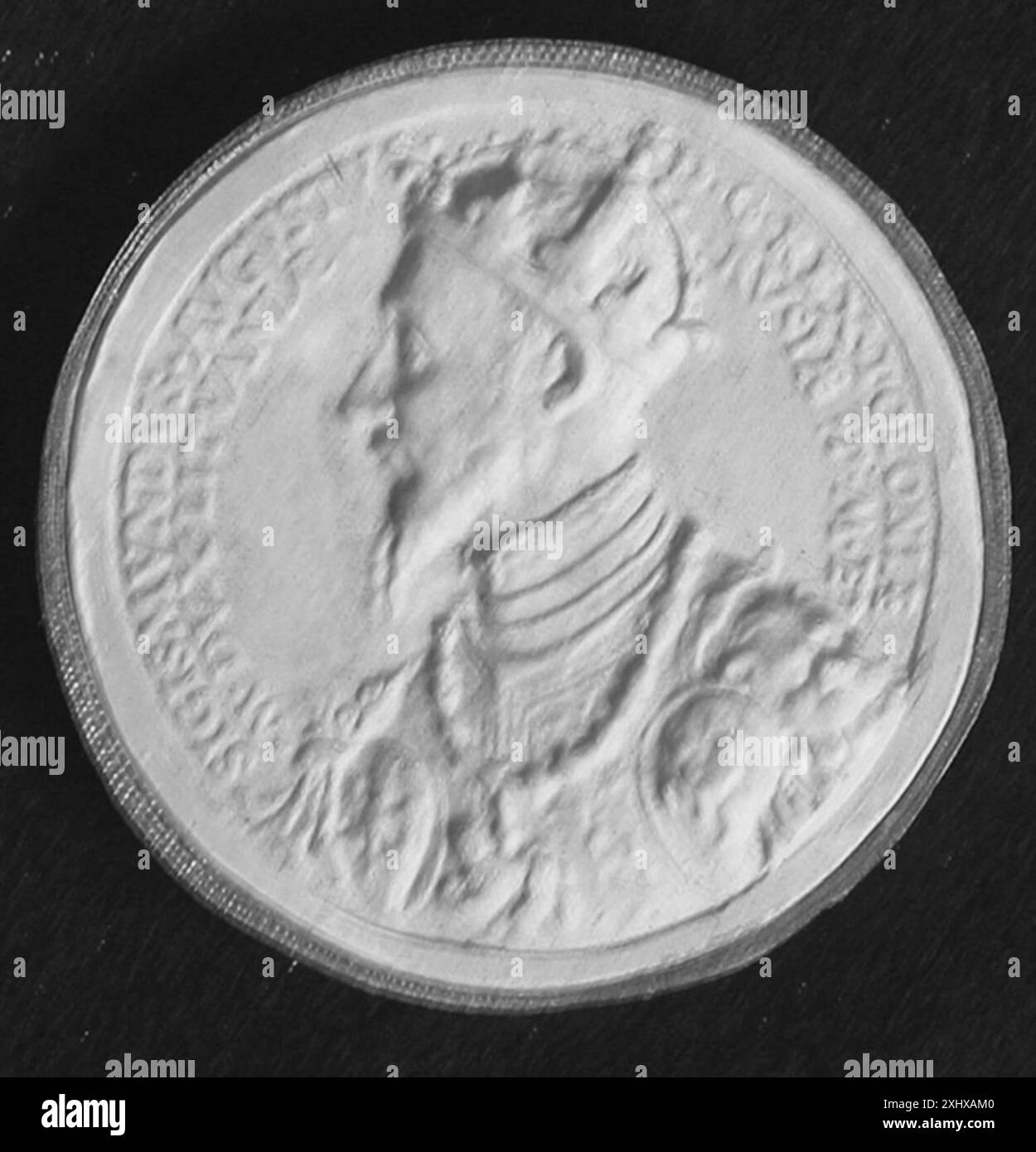 Oggetto circolare di tipo incerto, eventualmente una medaglia, un sigillo o una moneta, che mostri un disegno a rilievo o inciso, iscrizioni e caratteristiche del materiale metallico. Foto Stock