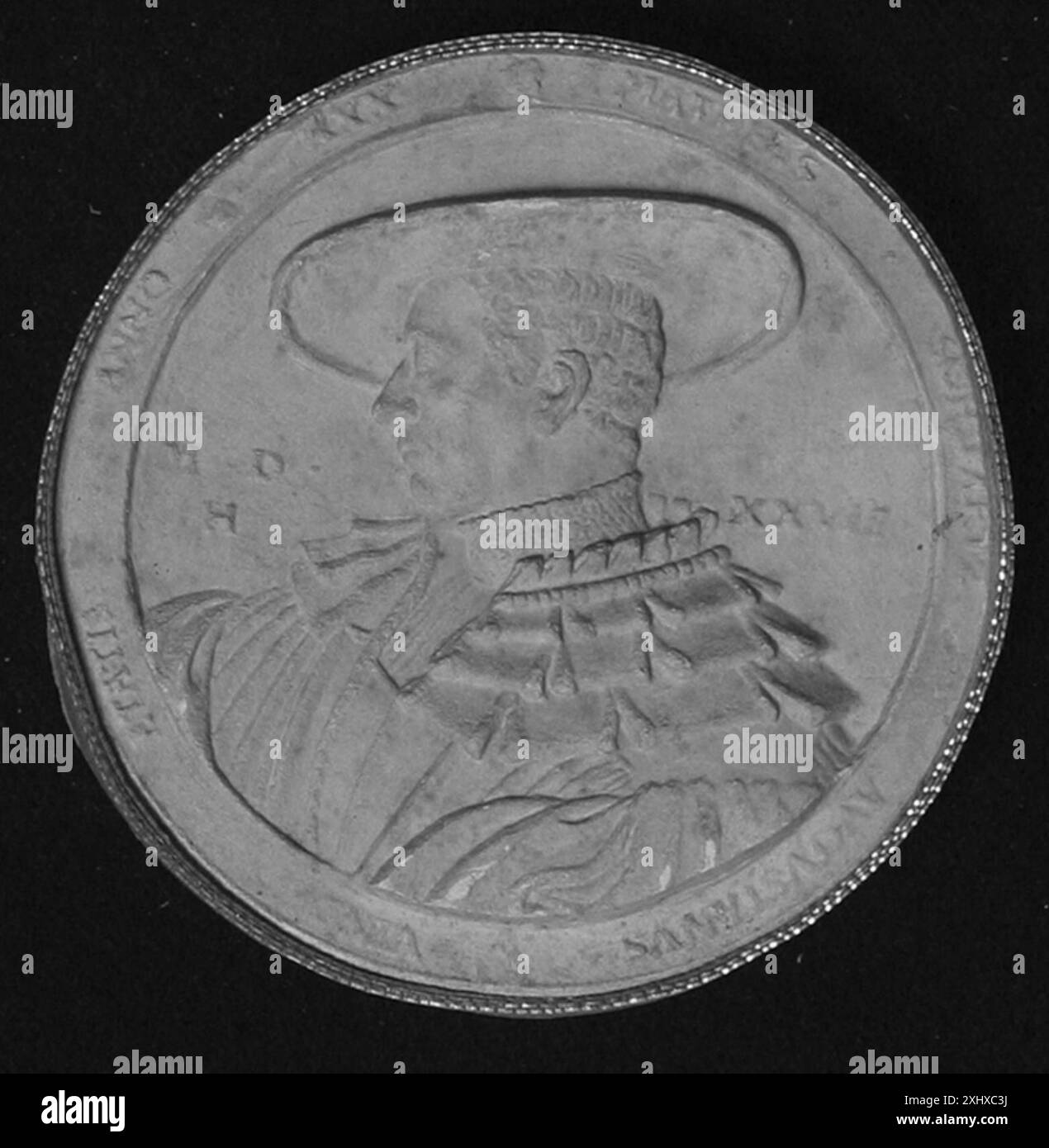 Un oggetto metallico circolare di tipo sconosciuto, forse una medaglia, un sigillo o una moneta, con decorazioni e iscrizioni in rilievo. Foto Stock