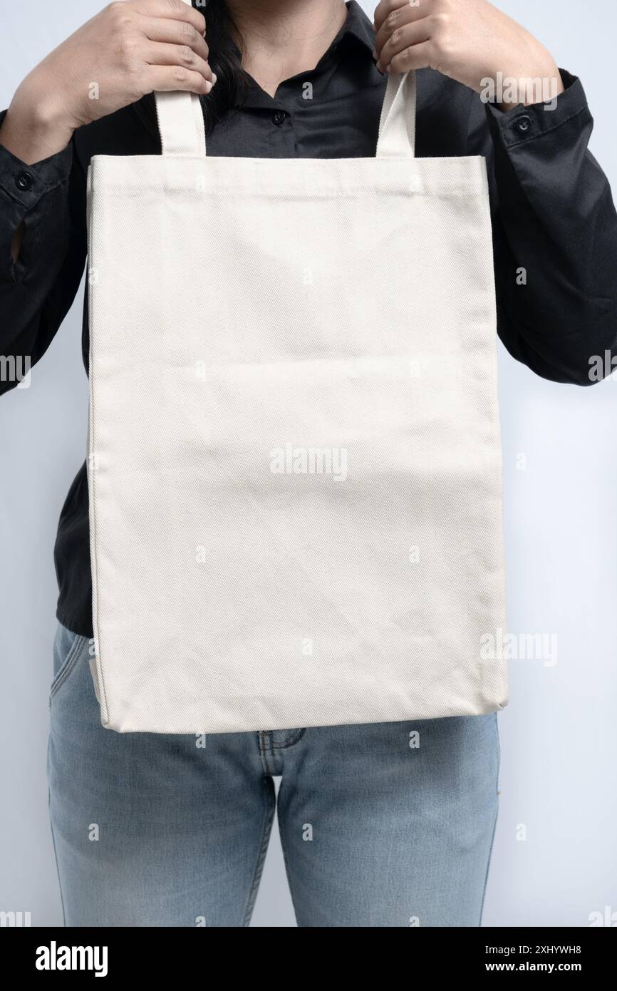 una donna che tiene in mano una borsa tote bianca vuota, utile per il design mockup Foto Stock