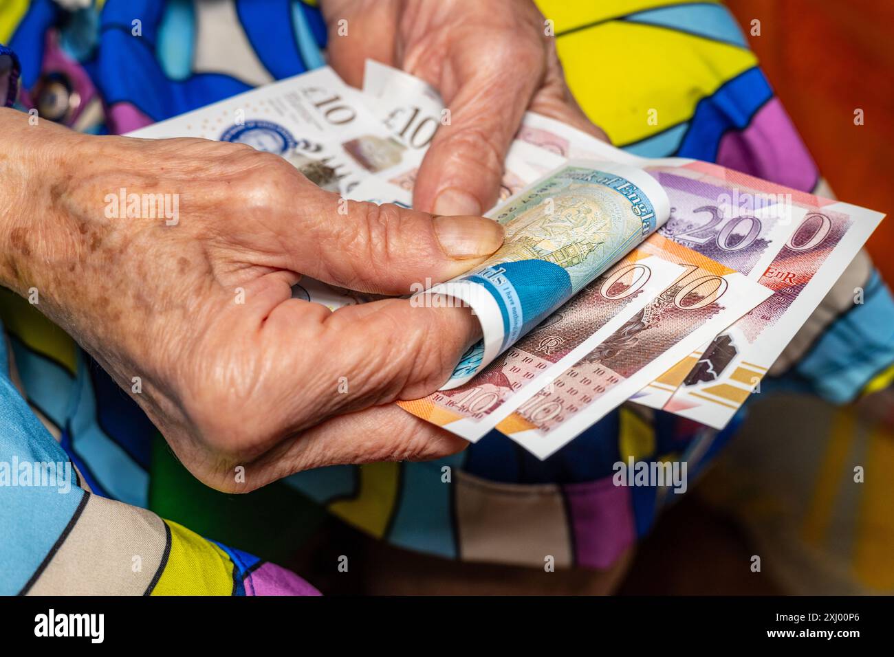 Le finanze dei pensionati. Una donna anziana converte sterline britanniche, pensioni e denaro degli anziani in Gran Bretagna. Primo piano Foto Stock