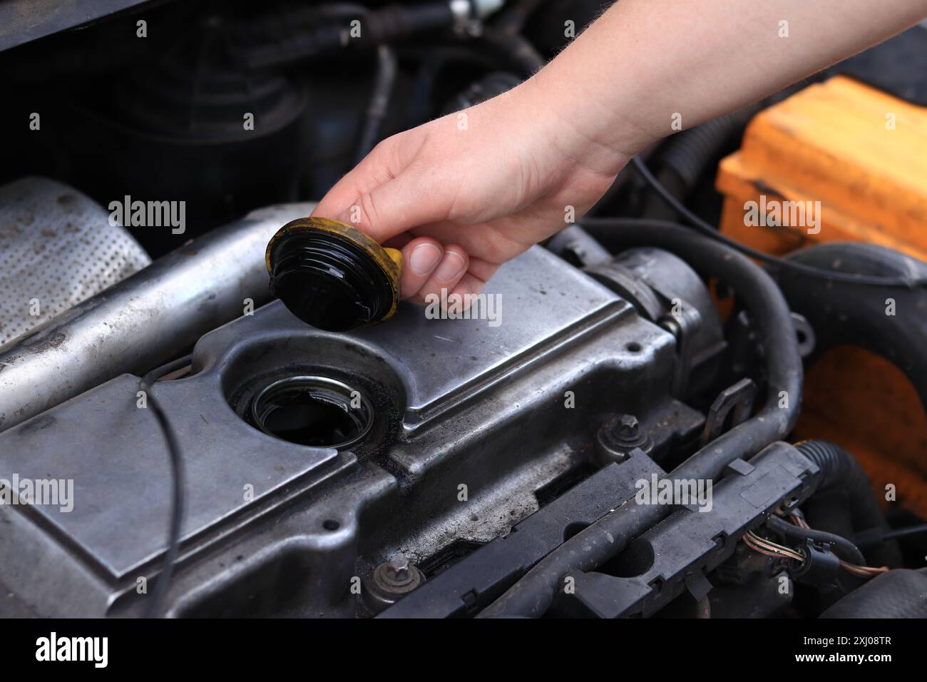 Cambio dell'olio. La mano di una donna apre o chiude il tappo del bocchettone di rifornimento dell'olio. Cambio dell'olio in un motore diesel. Manutenzione della vettura. Vecchia macchina Foto Stock