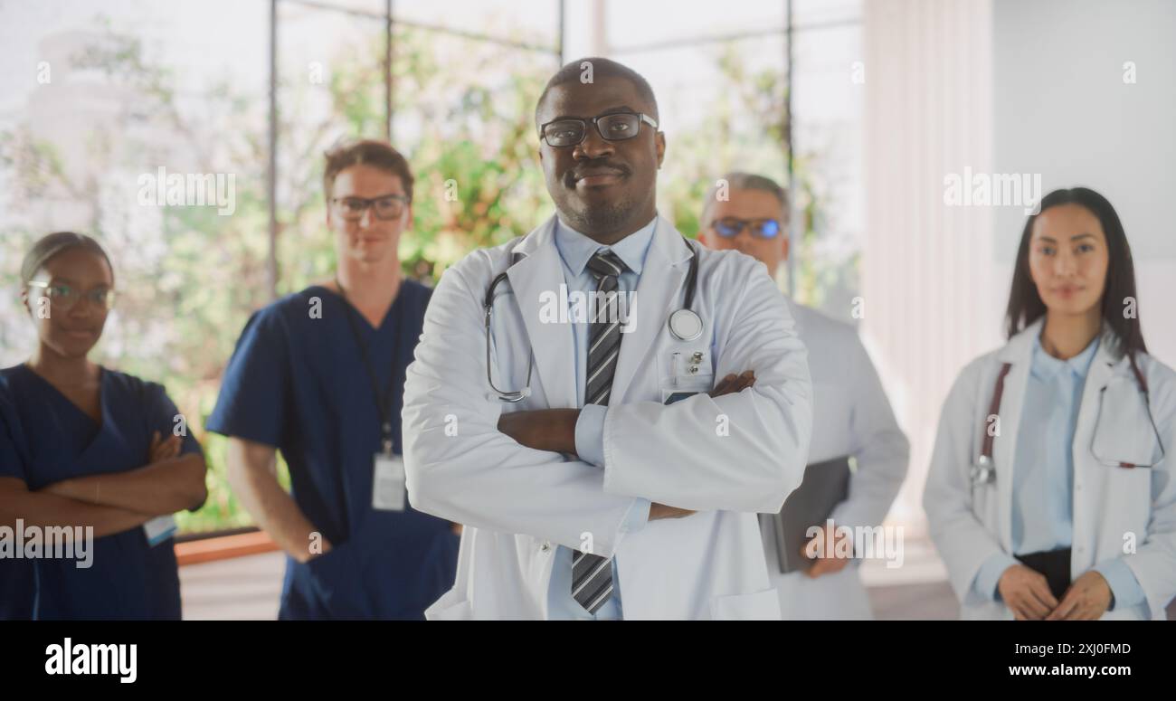 Team Portrait of a Female and male Successful Medical Healthcare Professionals Standing as a Group in a Modern Hospital Office. Medico afroamericano in piedi più vicino alla macchina fotografica Foto Stock