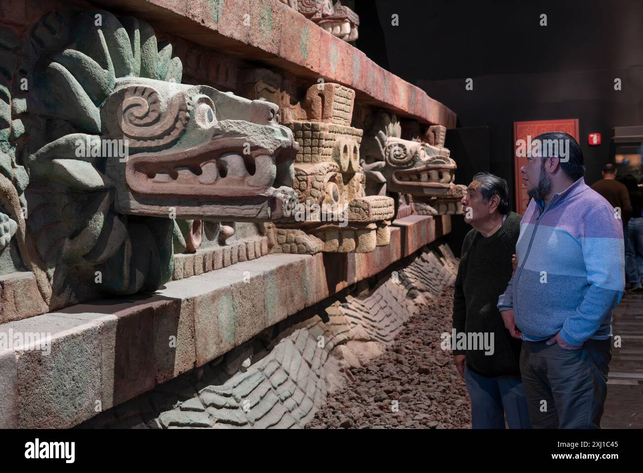 Due uomini che guardano una scultura in pietra scolpita in mostra riproduzione, il Tempio del Serpente piumato. Al Museo Nazionale di Antropologia a Coyoaca Foto Stock