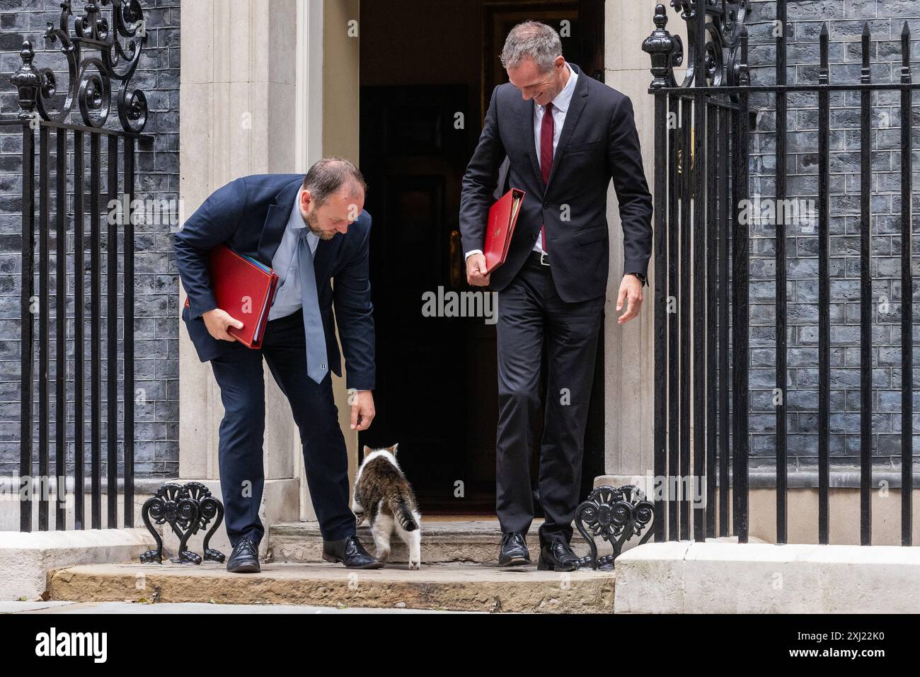 Londra, Regno Unito. 16 luglio 2024. Ian Murray deputato (l), Segretario di Stato per la Scozia, cerca di infastidire Larry il gatto mentre lascia 10 Downing Street con Peter Kyle deputato (r), Segretario di Stato per la Scienza, l'innovazione e la tecnologia, a seguito di una riunione del Gabinetto. Il primo ministro britannico Sir Keir Starmer ha comunicato che il suo nuovo governo deve "mettersi in moto” con particolare attenzione alla consegna. Crediti: Mark Kerrison/Alamy Live News Foto Stock