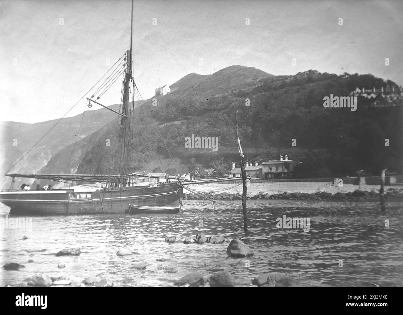 La foce del fiume Lyn con una barca sull'acqua e scogliere lontane. Lynmouth, Devon. Questa fotografia proviene da un originale edoardiano, intorno al 1910. L'originale faceva parte di un album di 150 fotografie di albume, di qualità variabile, molte delle quali ho fotografato. La collezione includeva immagini provenienti in particolare dall'Isola di Man e dalla contea inglese, Devonshire. Le annotazioni sono state incluse nell'album ma, sfortunatamente, non c'erano date specifiche. Le foto originali erano in media 6 x 4 ½ pollici. Foto Stock