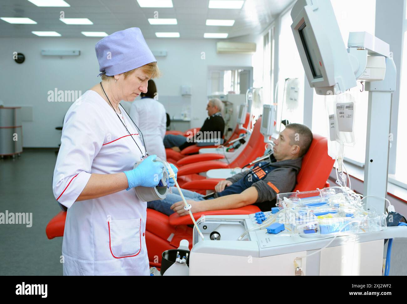 Presso la stazione di trasfusione di sangue municipale. Infermiere che prepara il separatore dell'apparato per trasfusioni di sangue, donatori sdraiati in letti d'ospedale. 5 aprile, Foto Stock