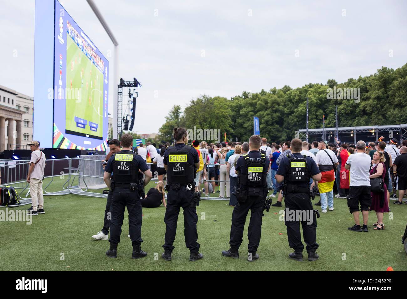 Quattro agenti di polizia guardano la parte anteriore della zona tifosi al Brandenburg Tor durante la partita del 16 tra Germania e Danimarca al Foto Stock