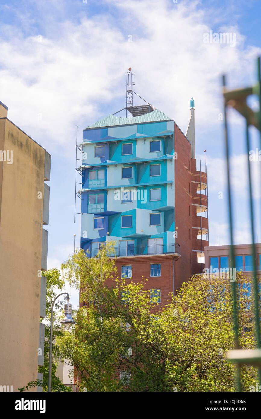 Un grattacielo colorato con un design insolito contro un cielo blu limpido circondato da alberi e altri edifici, Berlino, Germania Foto Stock