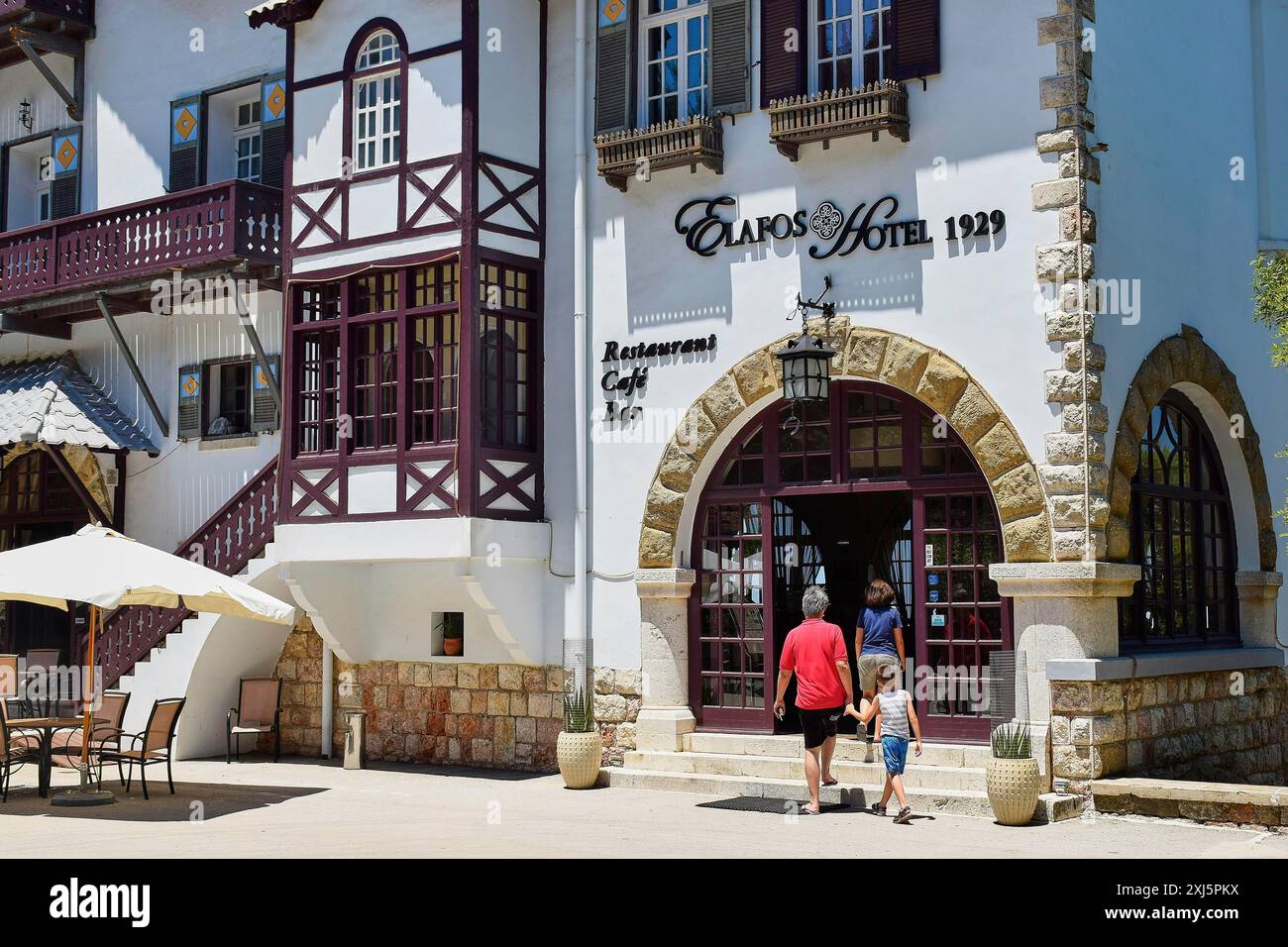 Ingresso di un hotel storico con graticcio, arco in pietra, ombrelloni e persone, Elafos Hotel, Profitis Ilias, Rodi, Dodecaneso, Isole greche Foto Stock