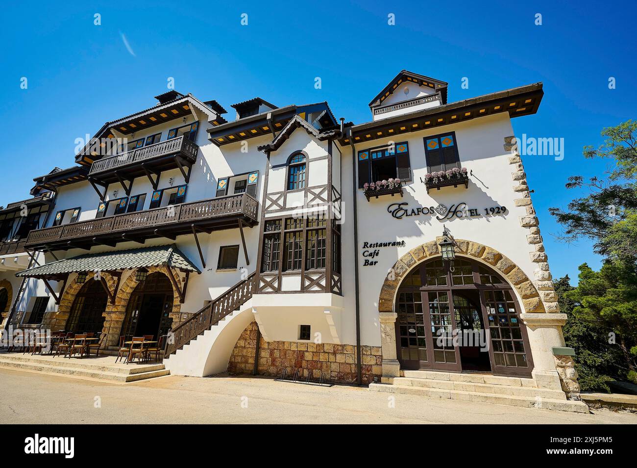 Storico hotel bianco con pareti a graticcio, balconi e ombrelloni in una giornata di sole, Elafos Hotel, Profitis Ilias, Rodi, Dodecaneso, greco Foto Stock