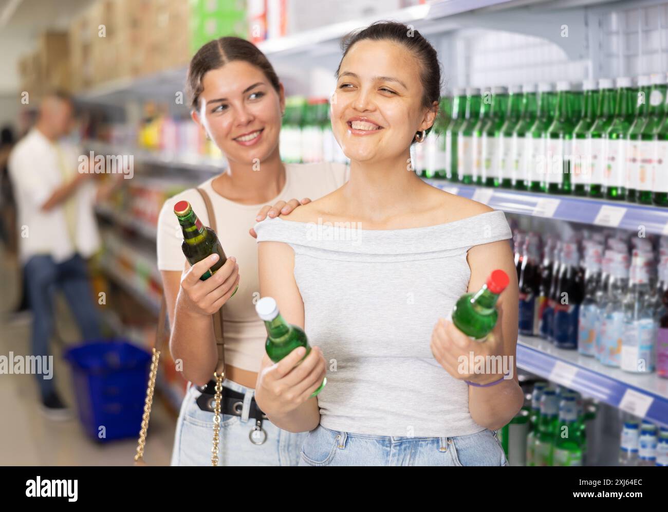 Giovani donne che discutono la scelta di bevande alcoliche nel supermercato Foto Stock