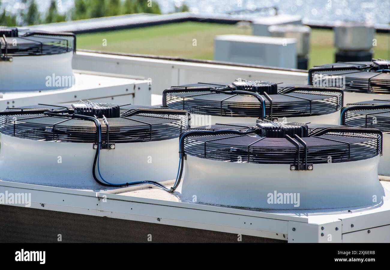 Vista ravvicinata di più unità HVAC commerciali sul tetto di un edificio. Questi sistemi di climatizzazione industriali sono dotati di ventole di raffreddamento e tec avanzato Foto Stock