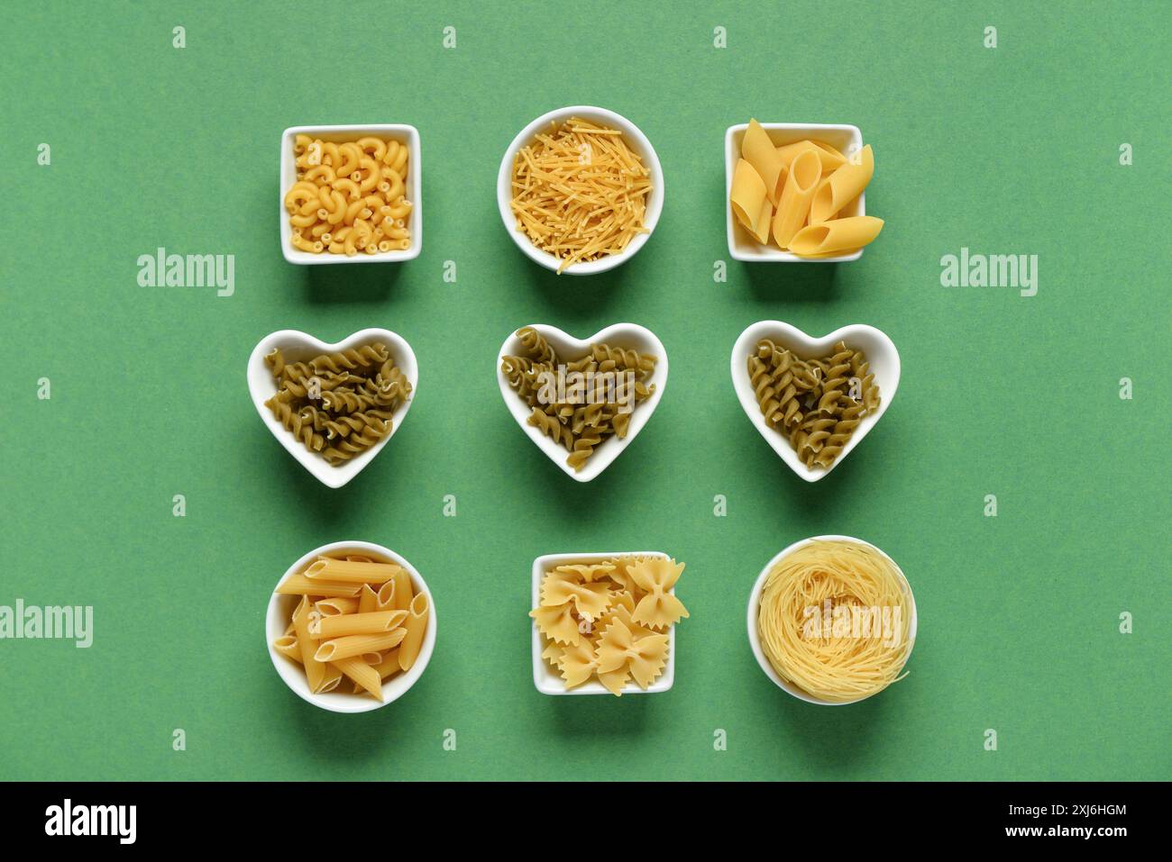 Ciotole con diversi tipi di deliziosa pasta cruda su sfondo verde Foto Stock