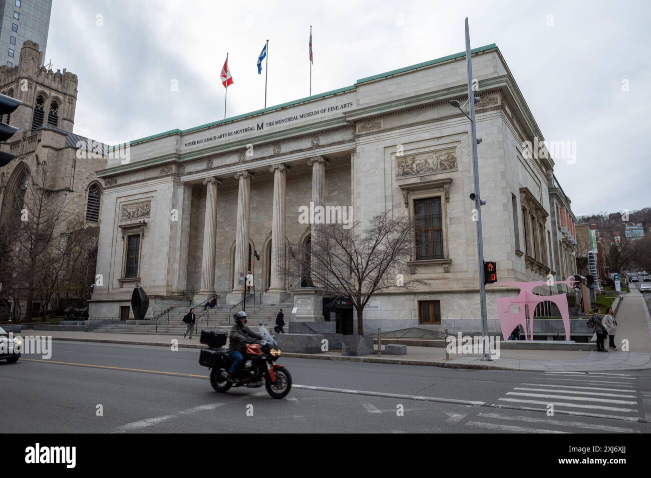 La splendida facciata del Museo delle Belle Arti di Montreal nel centro di Montreal, Canada, si erge maestosamente, con una elegante moto che guida davanti, b Foto Stock