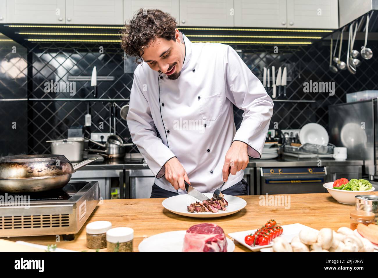 Lo chef felice il taglio di carne fritta con coltello e forchetta Foto Stock