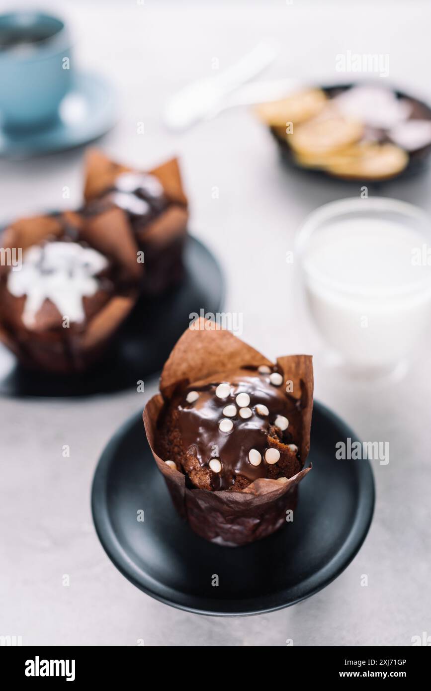 Dolce muffin al cioccolato con bicchiere di latte sul tavolo Foto Stock