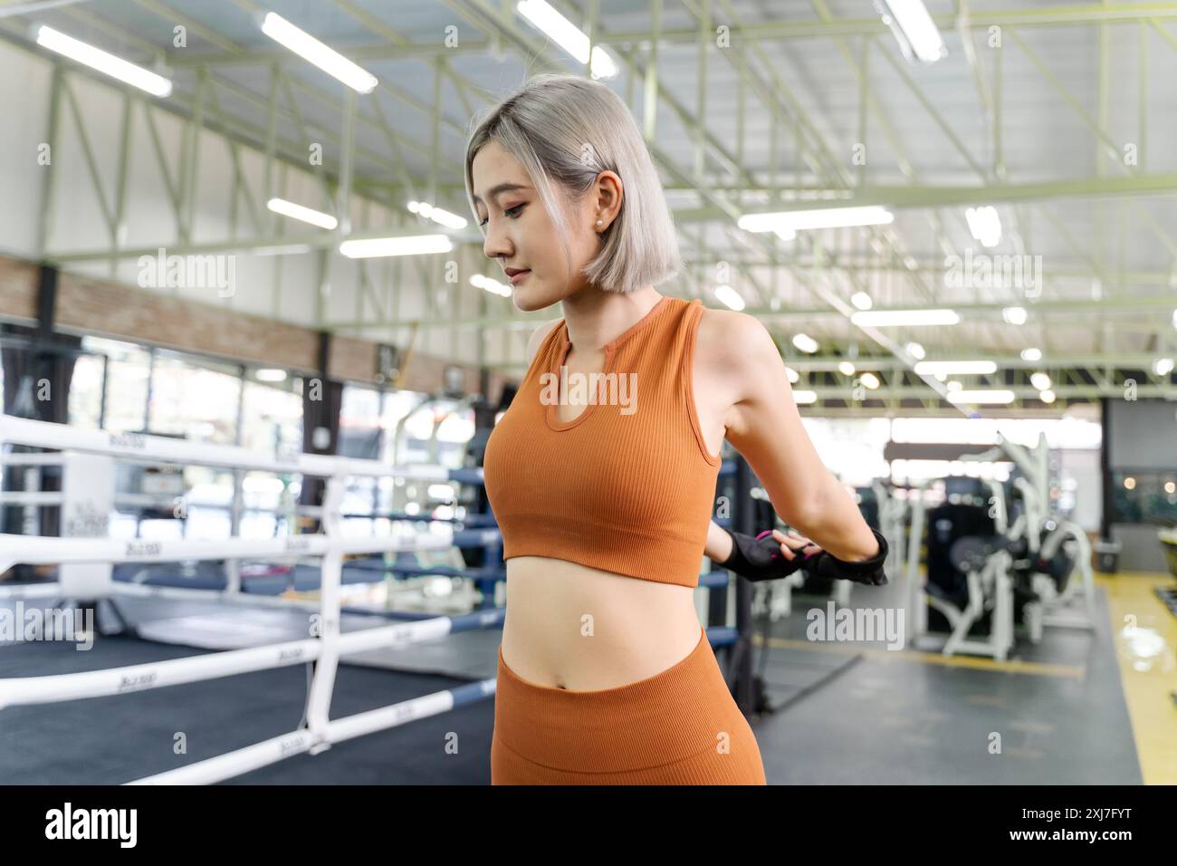 Giovane donna che si allunga le braccia e la parte superiore del corpo prima di iniziare il suo allenamento mattutino in una palestra locale Foto Stock