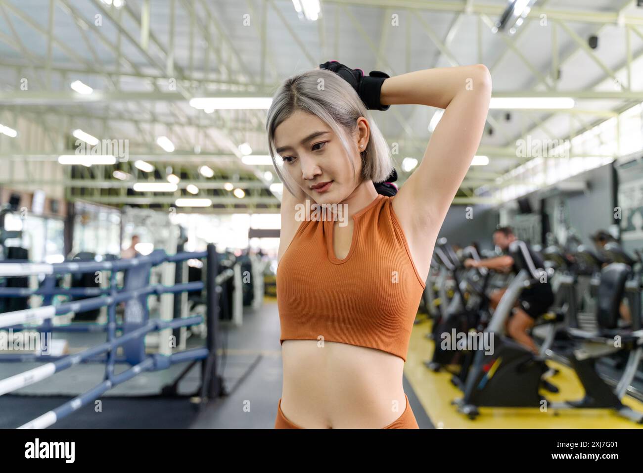 Giovane donna che si allunga le braccia e la parte superiore del corpo prima di iniziare il suo allenamento mattutino in una palestra locale Foto Stock