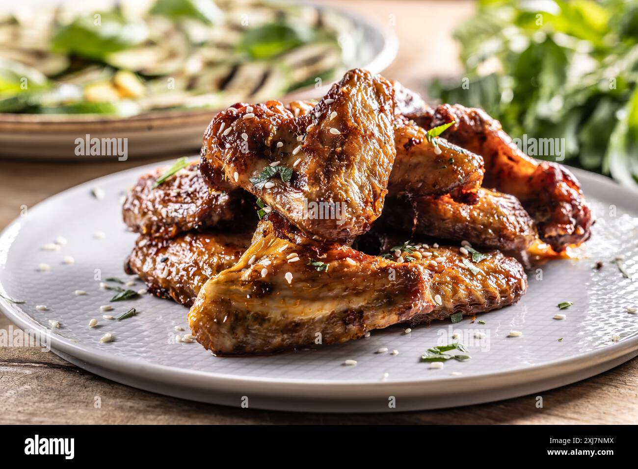 Ali di pollo grigliate su un piatto e zucchine grigliate come contorno. Foto Stock