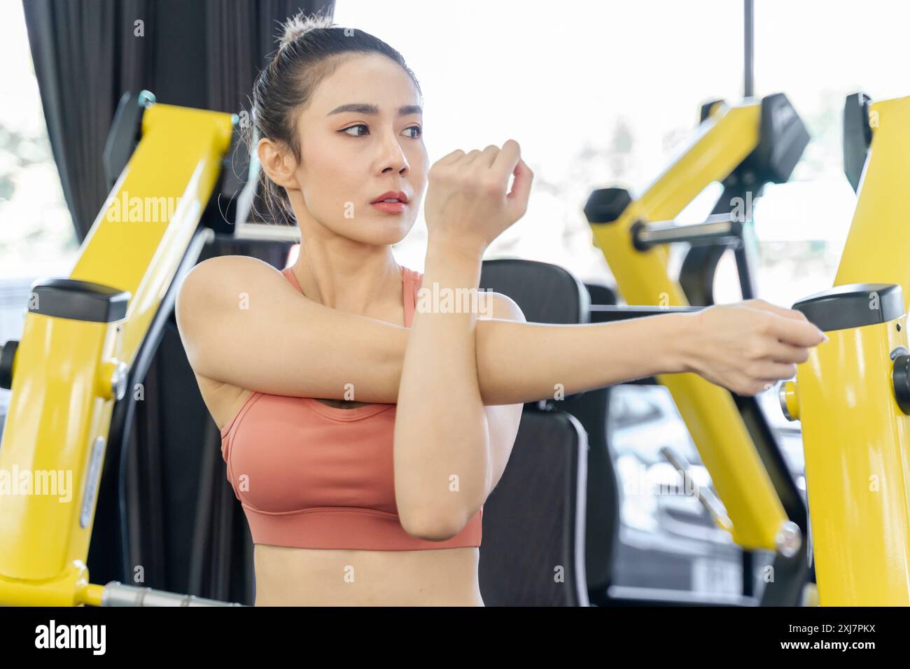 Giovane donna che si allunga le braccia e la parte superiore del corpo prima di iniziare il suo allenamento mattutino in una palestra locale Foto Stock