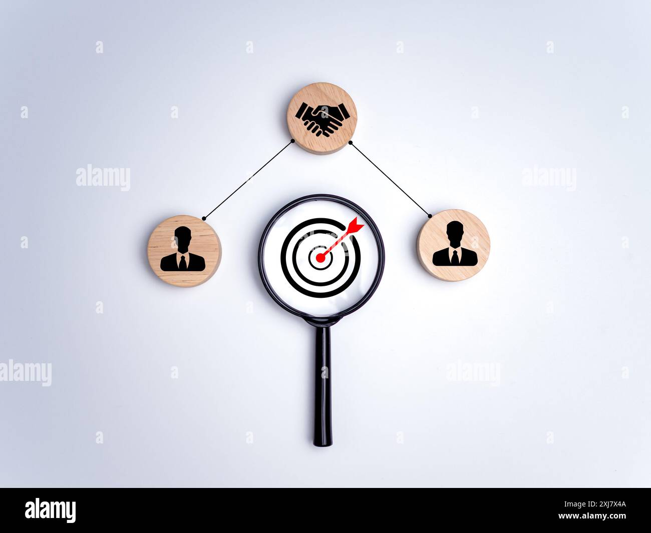 Lente d'ingrandimento con bordo di freccette e pezzi circolari di legno stampati con simboli umani, cooperazione, lavoro di squadra, formazione, collaborazione e cooperazione Foto Stock