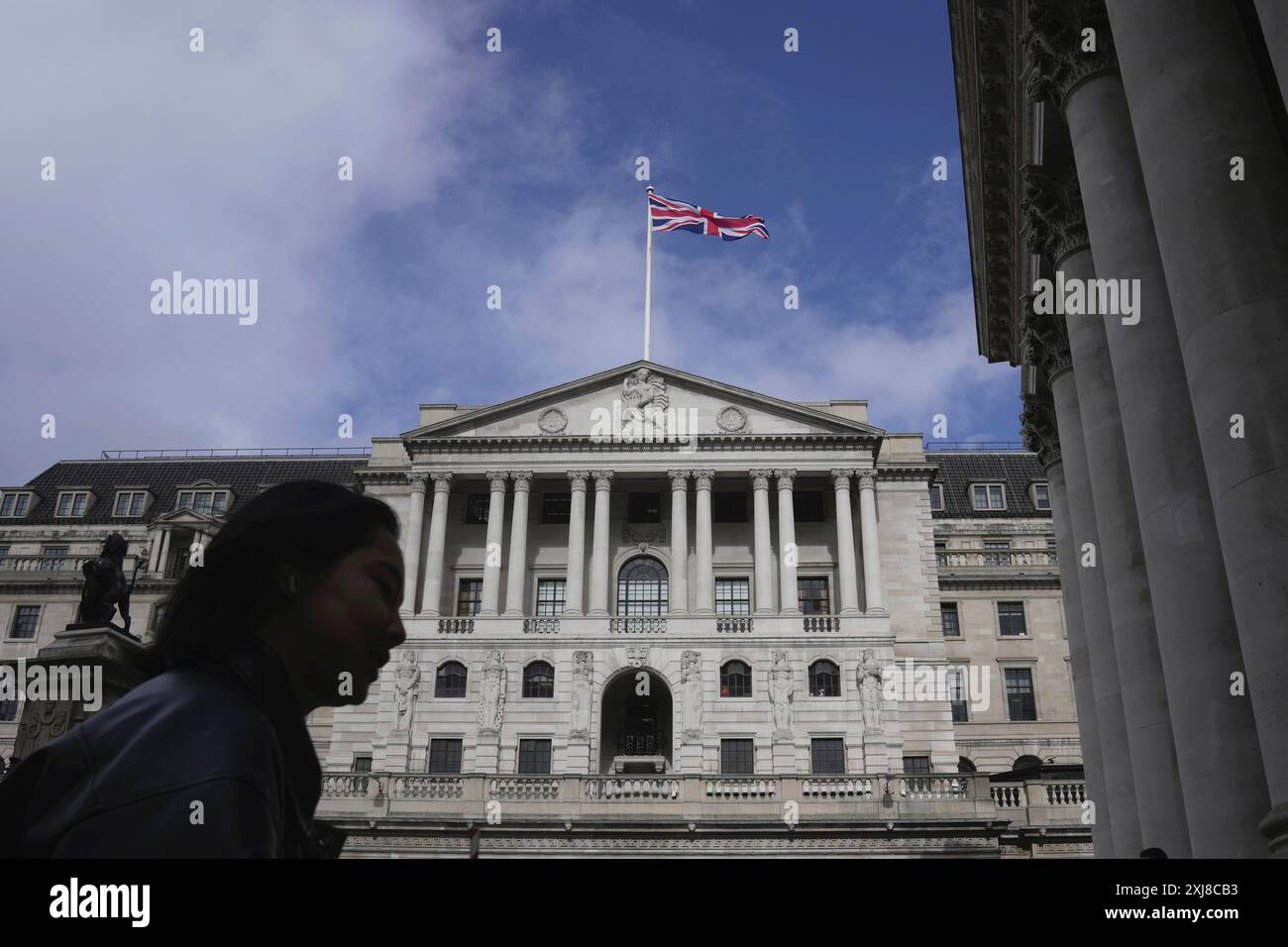FILE - A woman walks in front of the Bank of England, at the financial district in London, on March 23, 2023. Inflation in the U.K. held steady at the Bank of England's target rate of 2% in the year to June, official figures showed Wednesday, July 17, 2024, in a development that could be enough for policymakers to cut borrowing costs next month. (AP Photo/Kin Cheung, File) Foto Stock