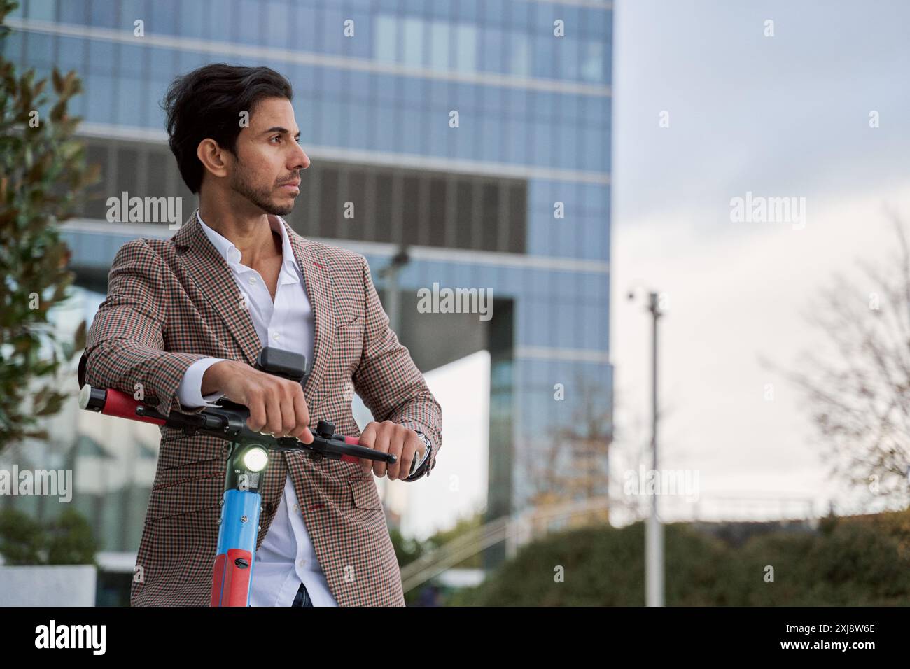 Ritratto di un uomo elegante appoggiato al suo scooter elettrico con spazio di copia per il testo. Foto Stock