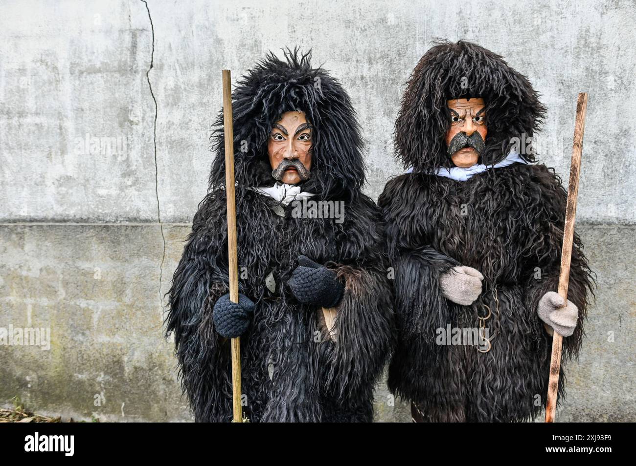 L'abbigliamento tradizionale del Carnevale di Sappada nelle Dolomiti è un'accattivante dimostrazione del ricco patrimonio culturale della regione. I partecipanti indossano costumi elaborati dai colori vivaci, ricami intricati e maschere in legno fatte a mano, ognuna realizzata in modo unico per rappresentare i vari personaggi del folklore locale. Il personaggio principale, Rollate, è particolarmente iconico: Una figura mascherata rivestita in pesante pelliccia di pecora scura con un grande cappuccio che copre completamente la testa, adornata da un ciuffo di lana rossa. La maschera di legno, con il suo aspetto poppa, baffi spessi scuri e sopracciglia, altera la voce del Foto Stock