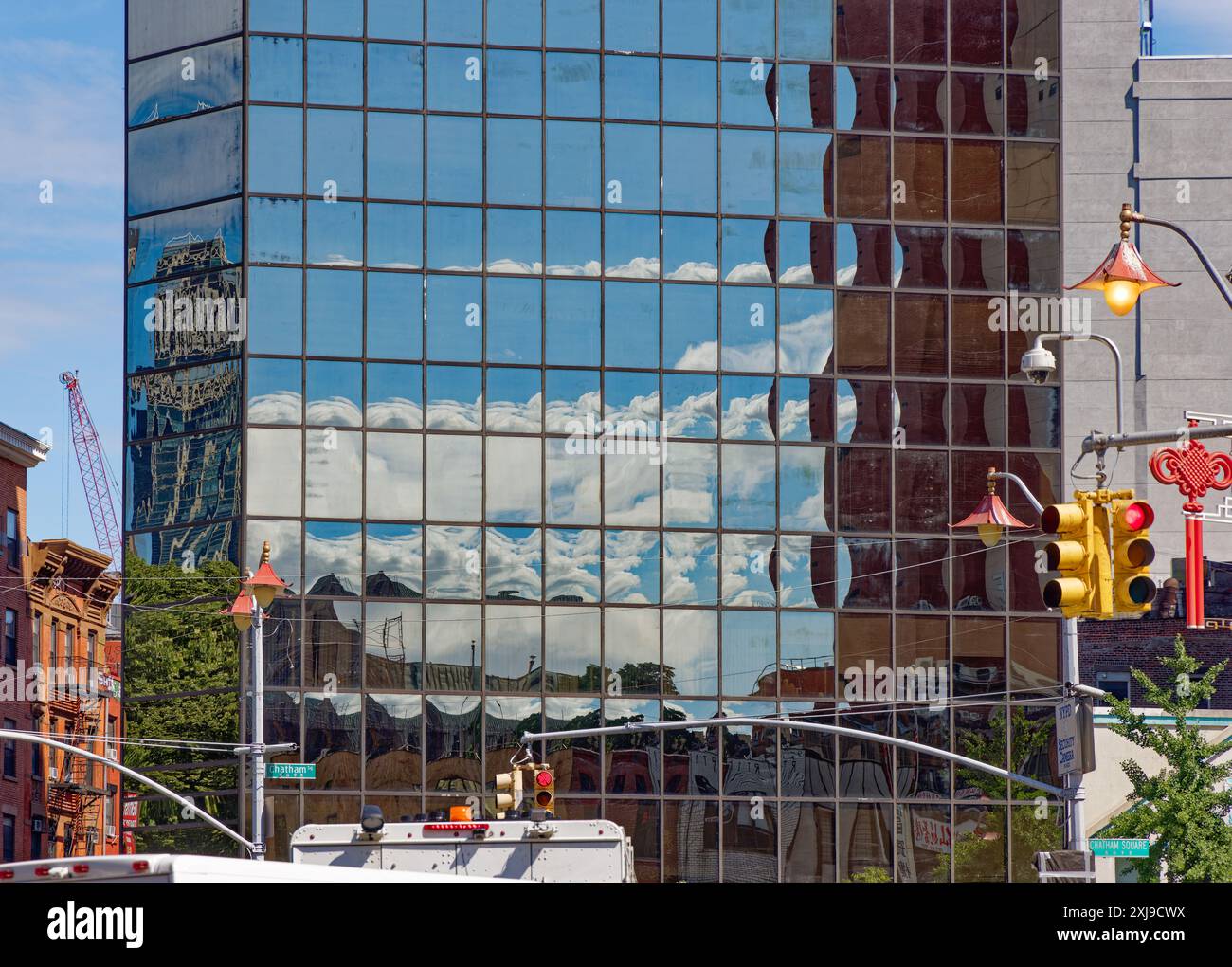 NYC Chinatown: La pelle nera di vetro a specchio di 2 Mott Street fornisce riflessi pixelati del cielo e degli edifici di Chatham Square/Five Points. Foto Stock