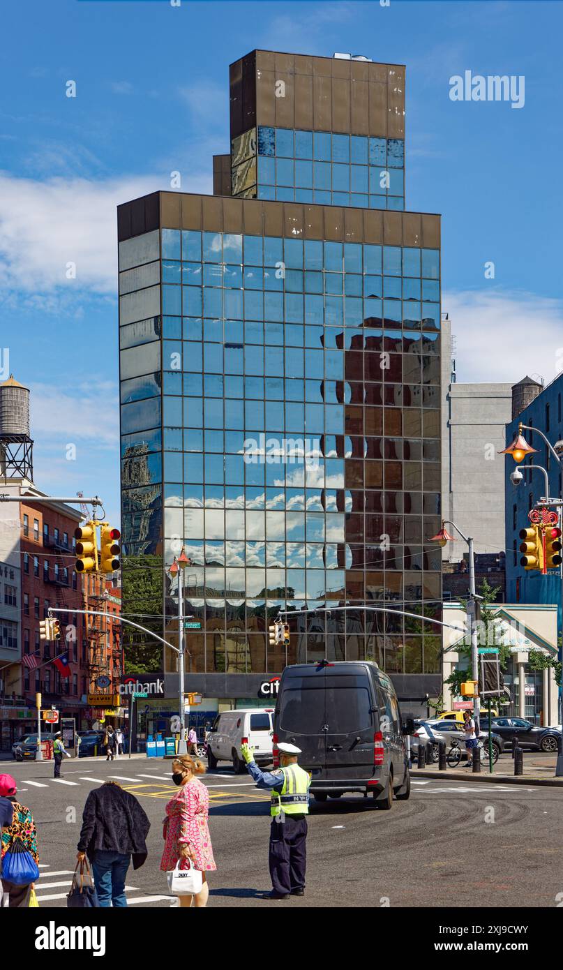 NYC Chinatown: La pelle nera di vetro a specchio di 2 Mott Street fornisce riflessi pixelati del cielo e degli edifici di Chatham Square/Five Points. Foto Stock