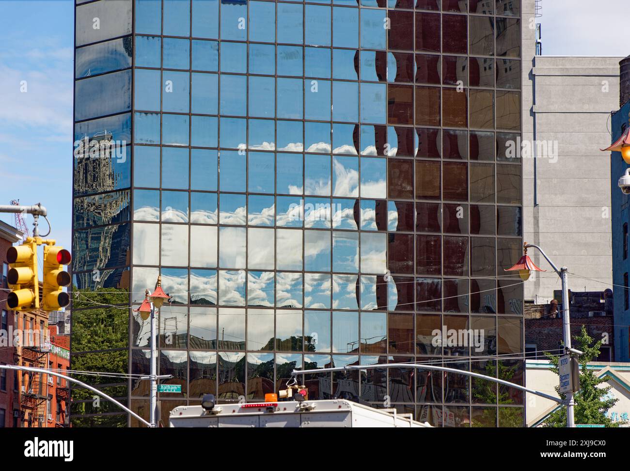 NYC Chinatown: La pelle nera di vetro a specchio di 2 Mott Street fornisce riflessi pixelati del cielo e degli edifici di Chatham Square/Five Points. Foto Stock