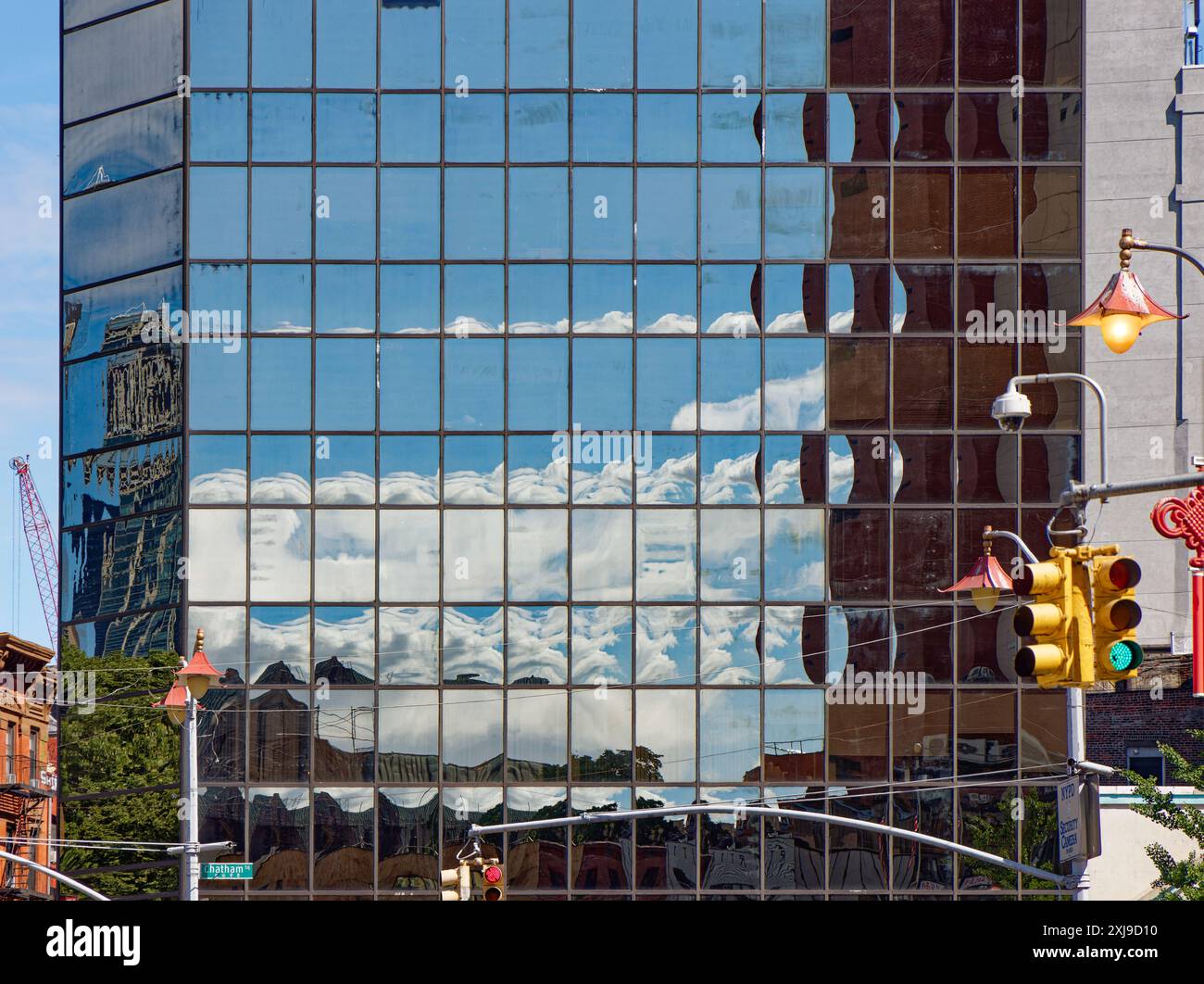 NYC Chinatown: La pelle nera di vetro a specchio di 2 Mott Street fornisce riflessi pixelati del cielo e degli edifici di Chatham Square/Five Points. Foto Stock