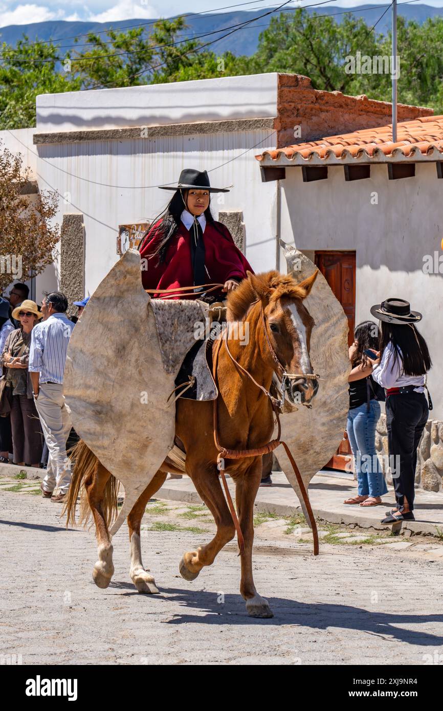 Una gaucho femminile che indossa un tradizionale poncho rosso Salteño in una parata a cachi, Argentina. Tradizionalmente chiamata "cina", che è un Quec indigeno Foto Stock